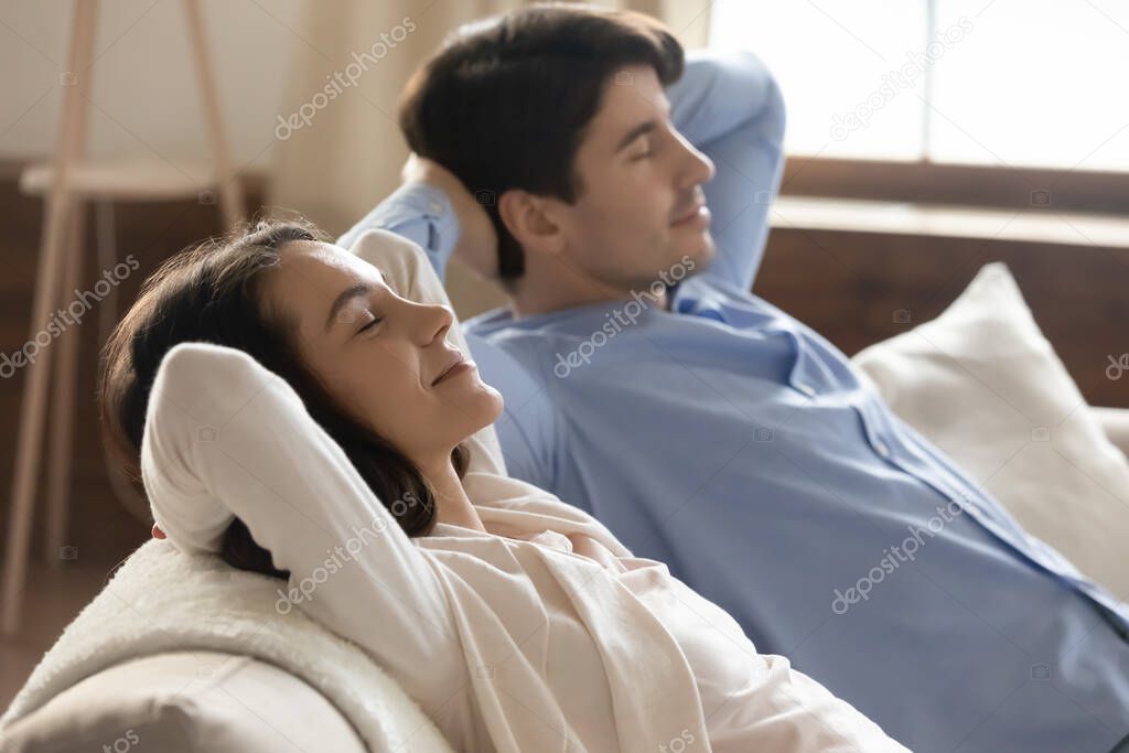 Serene married couple napping on couch enjoying relax and peace
