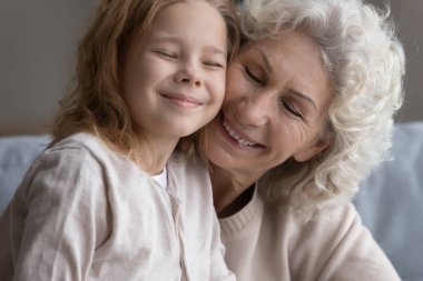 Gülümseyen olgun bir kadın, küçük torununa sarılıyor.