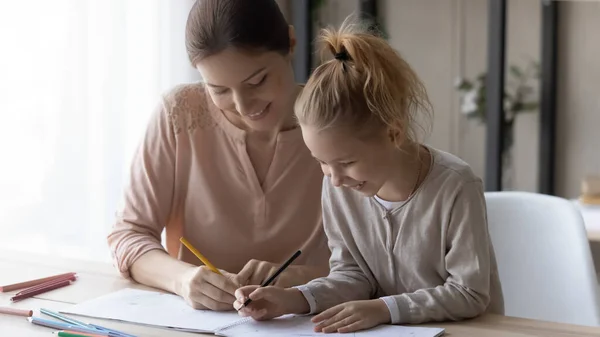 Mujer joven feliz con su hija pequeña dibujando lápices de colores —  Fotos de Stock