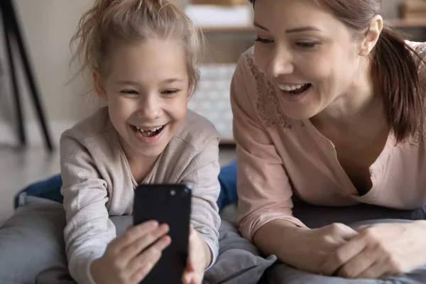 Закрыть радостную девочку и маму, веселящихся с телефоном — стоковое фото