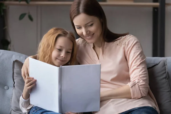 Sonriente joven madre enseñando a su hijita a leer —  Fotos de Stock