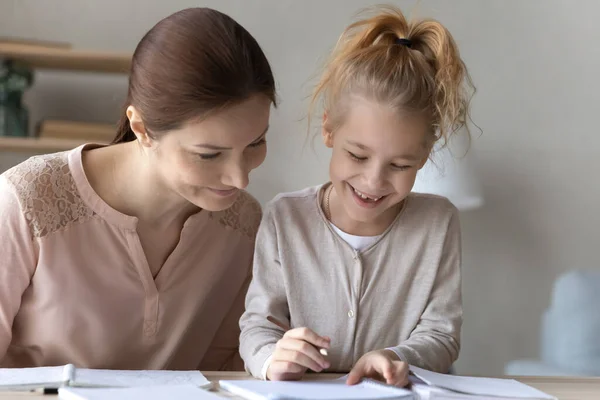 Madre premurosa e sorridente bambina che fa i compiti a scuola insieme — Foto Stock