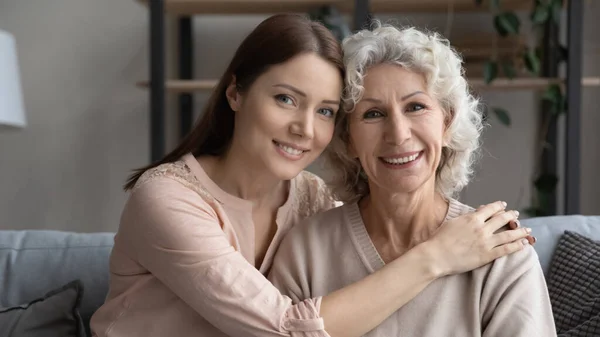 Tiro en la cabeza sonriente mujer joven con madre anciana abrazando —  Fotos de Stock