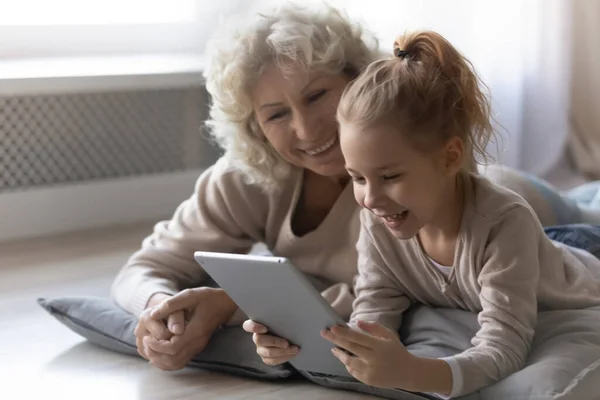 Rindo menina com avó madura se divertindo com tablet — Fotografia de Stock