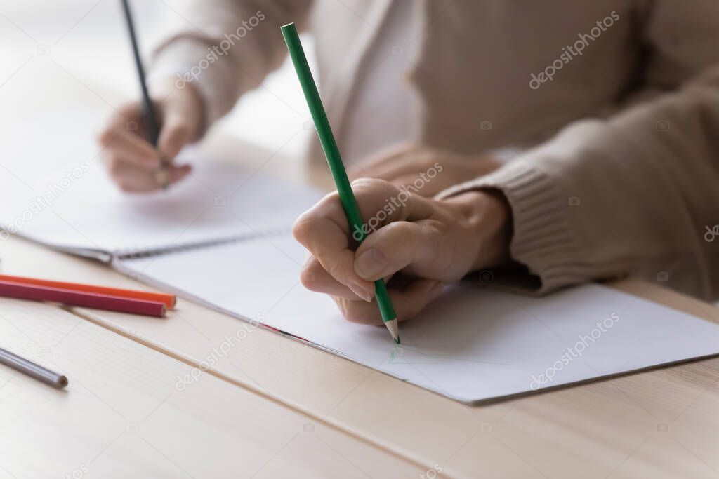 Close up mature grandmother and little girl drawing together