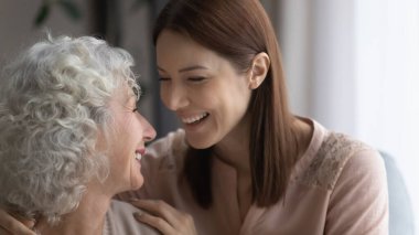 Çok neşeli genç bir kadın, olgun bir anne gülüyor.