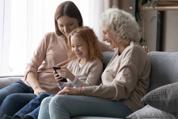 Niña feliz con madre y abuela usando smartphone — Foto de Stock