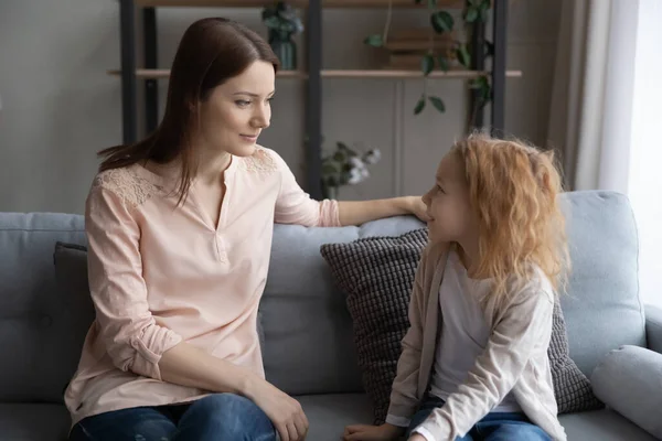 Feliz joven madre y niña hablando, sentado en el sofá — Foto de Stock