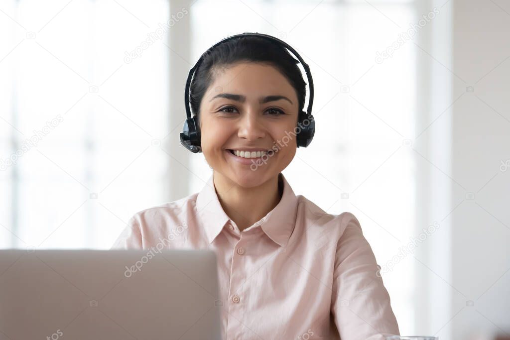 Headshot portrait of smiling indian worker in headphones
