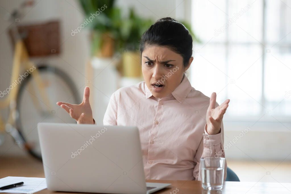 Unhappy young indian woman frustrated by laptop problem