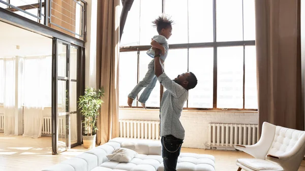 Forte jeune homme afro-américain élever dans l'air enfant fils. — Photo