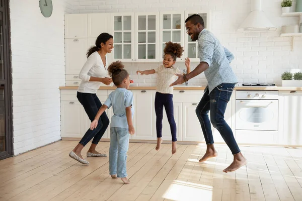 Överlycklig afrikansk amerikansk par hoppar med glada energiska barn. — Stockfoto