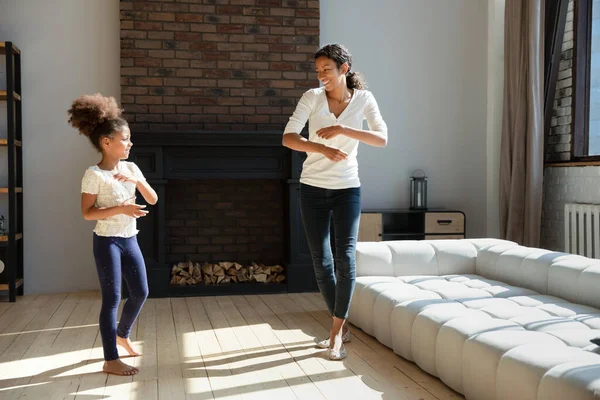 Pequeña niña repitiendo divertidos movimientos disco después de la madre. — Foto de Stock