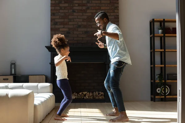Glad liten afrikansk amerikansk unge som dansar med pappa i vardagsrummet. — Stockfoto