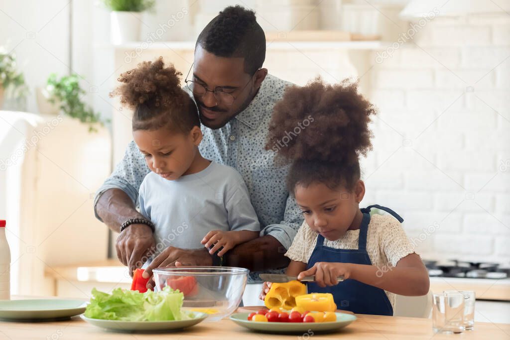 Happy biracial family involved in cooking tasty vegetarian dishes.
