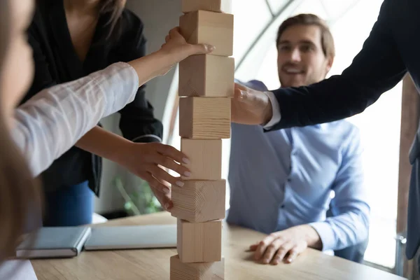 Focus da vicino sulla torre in blocchi di legno, costruita da compagni di squadra felici. — Foto Stock