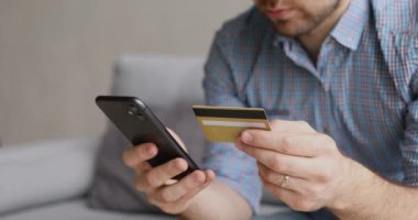 Mobil uygulamayla kredi kartı bilgilerini girerken odaklanmış genç adam.