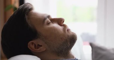 Rahat genç adam rahat bir kanepeye yaslanmış uyuyor..