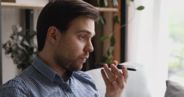 Gülümseyen genç adam akıllı telefondan sesli mesaj kaydediyor..
