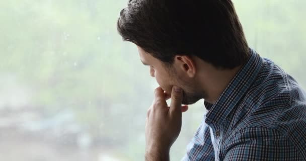 Stressato giovane uomo infelice guardando fuori dalla finestra. — Video Stock