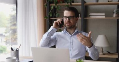 Gözlüklü mutlu genç işadamı elinde cep telefonuyla arıyor..