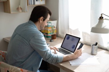 Konsantre genç işadamı pazarlama araştırma grafiklerini analiz ediyor.