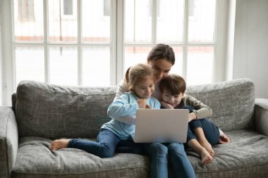 Sevgi dolu anne çocuklarla dizüstü bilgisayarda video izliyor.
