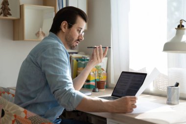 Mobil uygulamada sesli mesaj dikte eden konsantre genç adam.