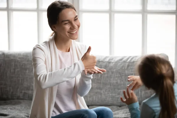 Sonriente mamá utilizar el lenguaje de señas hablando con su hija pequeña — Foto de Stock