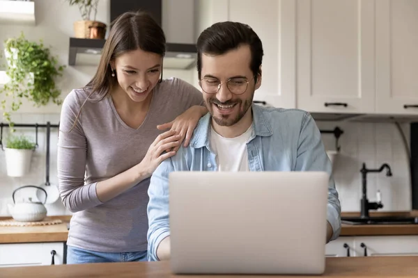 Gelukkig jong liefdevol familie paar op zoek naar laptop scherm. — Stockfoto