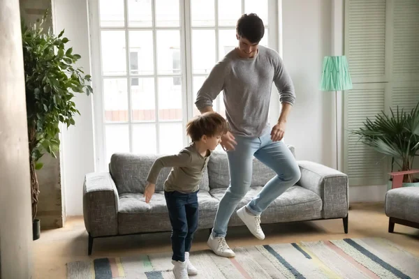 Šťastný otec tančí s malým vzrušeným synem doma — Stock fotografie