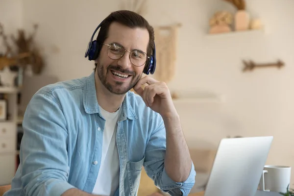 Portret van een lachende jongeman met een draadloze hoofdtelefoon. — Stockfoto