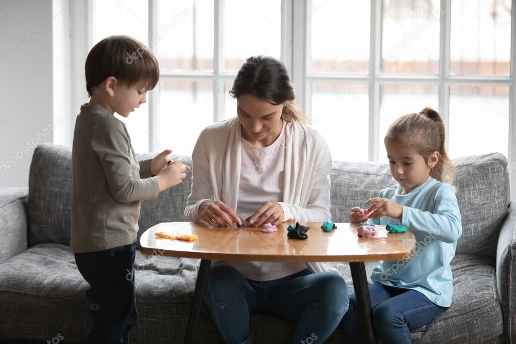 Young mom and small kids play with plasticine at home