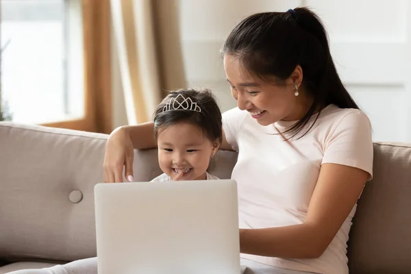 Happy Asian young mother and little daughter using laptop together — Stock Photo, Image