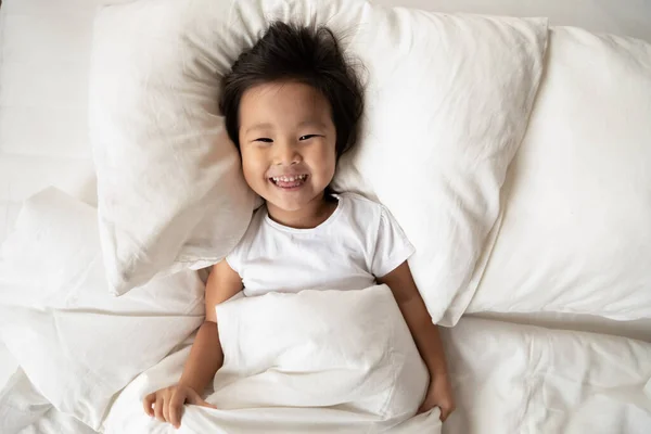 Top pohled portrét úsměv roztomilé asijské holčička v posteli — Stock fotografie