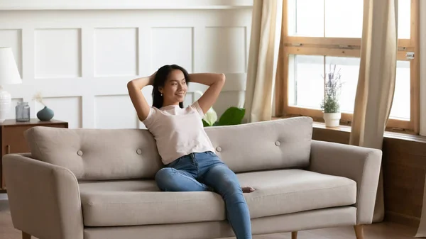 Satisfied dreamy young Asian woman relaxing on cozy couch — Stock Photo, Image