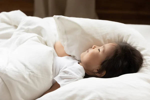 Close up klidný asijské holčička spací v útulný lůžko — Stock fotografie