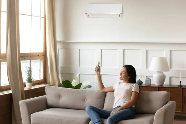 Smiling Asian young woman using air conditioner remote controller — Stock Photo, Image