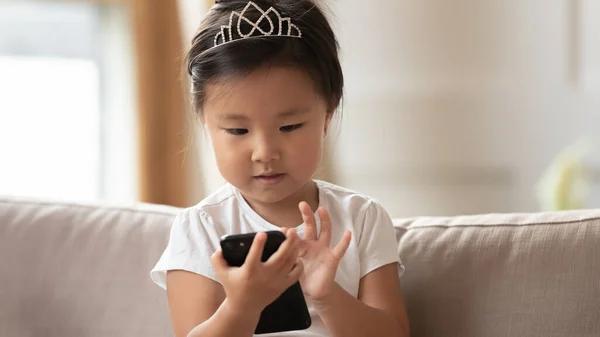 Close up cute little girl wearing princess diadem using smartphone — Stock Photo, Image