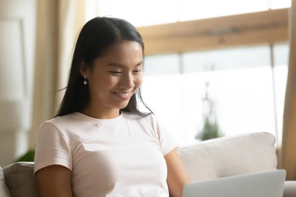 De cerca sonriendo joven mujer asiática mirando a la pantalla del ordenador portátil — Foto de Stock