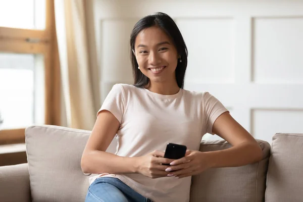 Retrato sonriente mujer asiática sosteniendo teléfono inteligente, mirando a la cámara — Foto de Stock