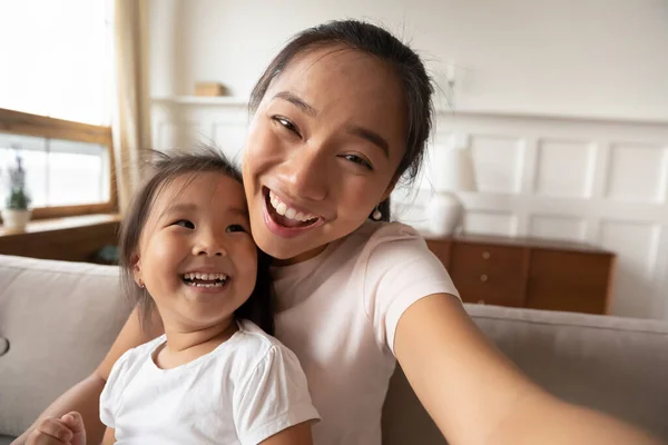 Close up smiling Asian mother and little girl taking selfie — Stock Photo, Image