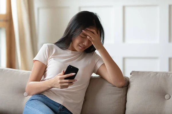 Zaklatott fiatal ázsiai nő sír, kezében telefon, kapott rossz üzenetet — Stock Fotó