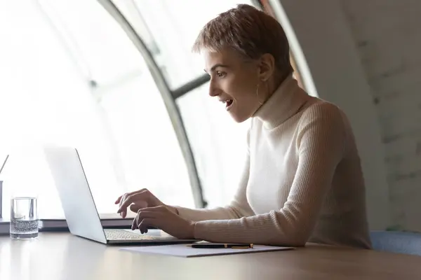 Excited female employee surprised by news on laptop — Stock Photo, Image