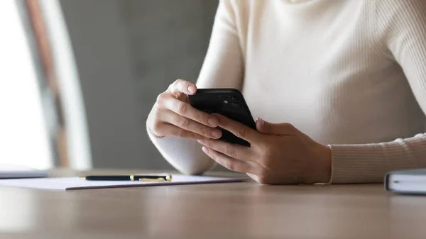 Закрыть женщину, сидящую за столом с помощью смартфона — стоковое фото