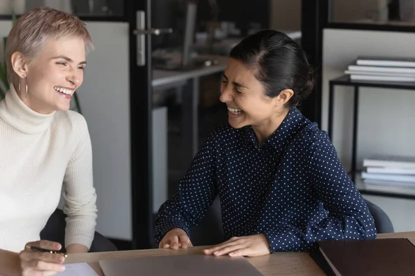 Overjoyed multiracial female colleagues laugh at workplace — Stock Photo, Image