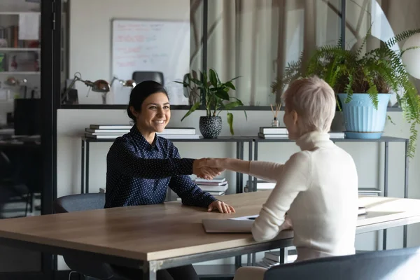 Smiling multiracial female colleagues handshake at meeting — Stock Photo, Image