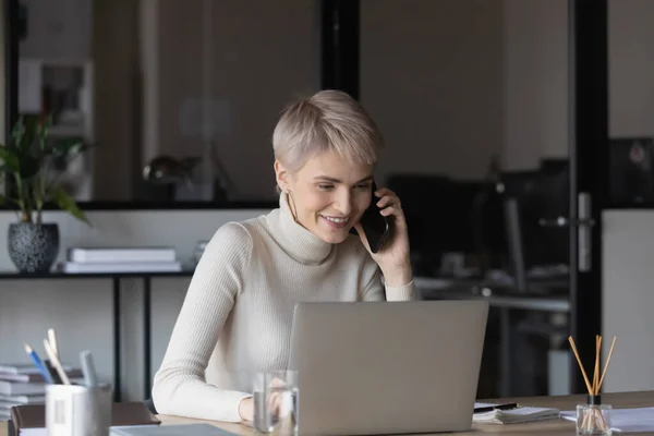 Smiling businesswoman work on computer talking on cell — Stock Photo, Image