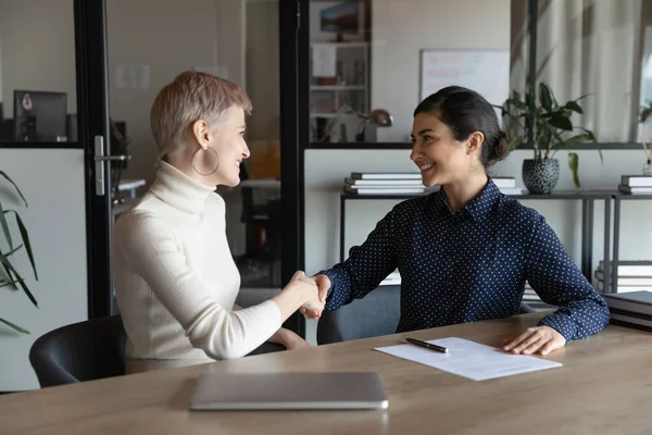 Smiling multiracial female colleagues handshake at meeting — Stock Photo, Image