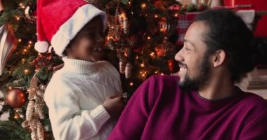 Afrikalı oğul, Noel ağacında poz veren babasına sarılıyor.